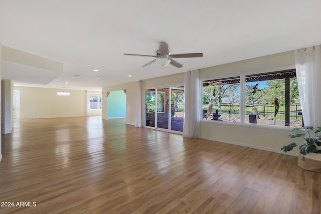 unfurnished living room featuring a healthy amount of sunlight, light wood finished floors, and ceiling fan with notable chandelier