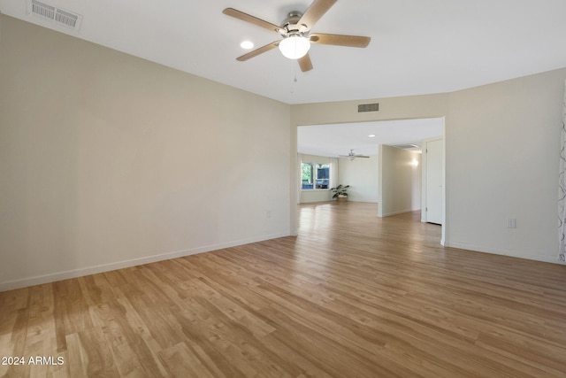 empty room with light wood-style flooring, visible vents, and baseboards