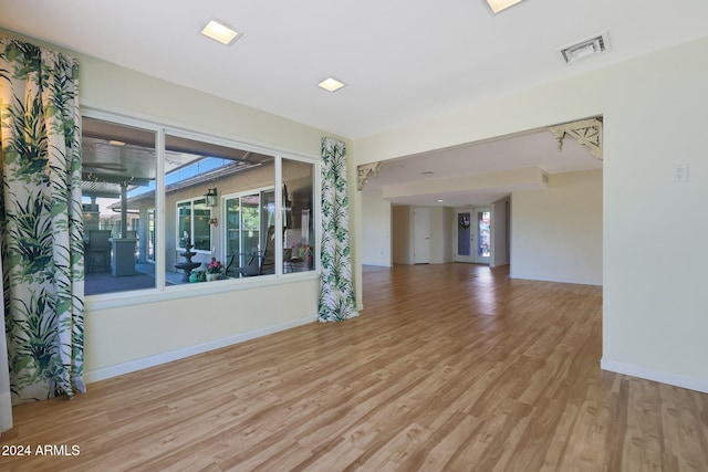 unfurnished room featuring plenty of natural light, wood finished floors, visible vents, and baseboards