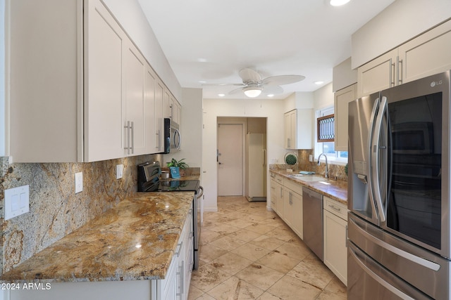 kitchen with tasteful backsplash, ceiling fan, appliances with stainless steel finishes, light stone countertops, and a sink