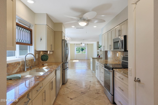 kitchen featuring stainless steel appliances, tasteful backsplash, visible vents, a sink, and light stone countertops