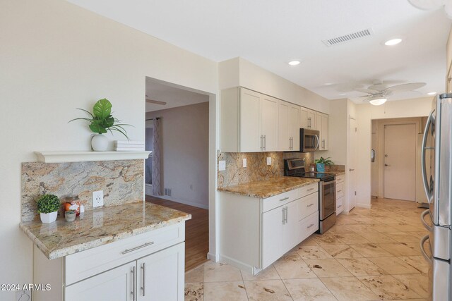 kitchen with visible vents, a ceiling fan, stainless steel appliances, white cabinetry, and backsplash