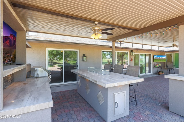 view of patio featuring area for grilling, outdoor wet bar, grilling area, and a ceiling fan