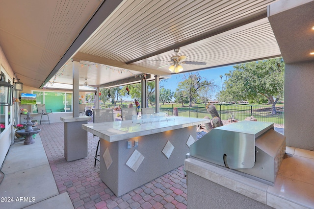 view of patio featuring ceiling fan, fence, outdoor wet bar, and area for grilling