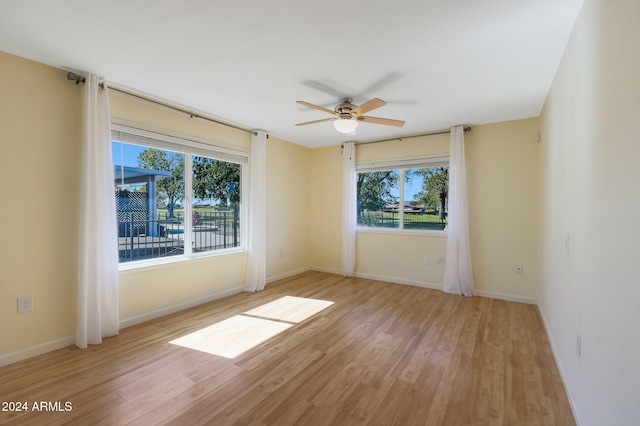 unfurnished room featuring baseboards, a wealth of natural light, and light wood-style floors