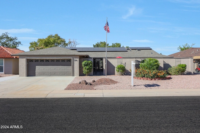 view of front of property with concrete driveway, stucco siding, an attached garage, and solar panels