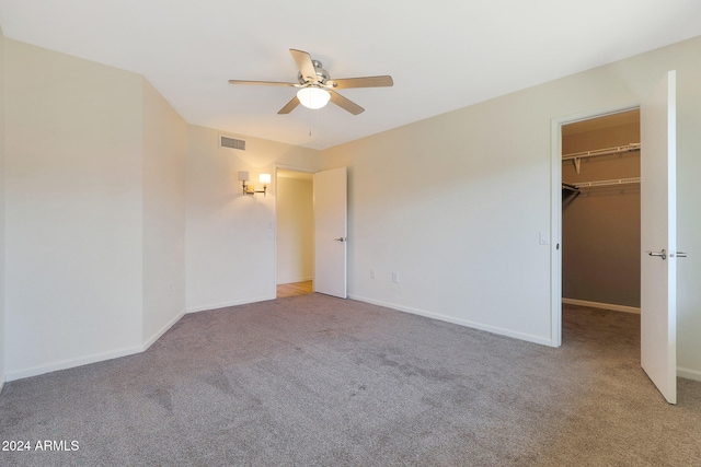 unfurnished bedroom featuring baseboards, visible vents, a ceiling fan, a spacious closet, and carpet flooring