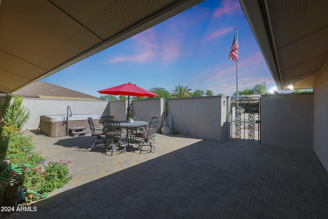 view of patio / terrace featuring a hot tub, a gate, fence, and outdoor dining space