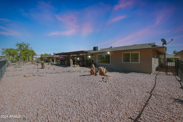 back of house at dusk featuring fence and stucco siding