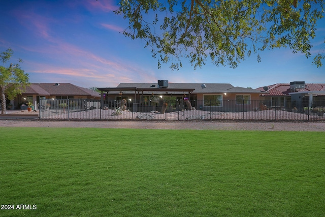 rear view of house with a lawn and fence