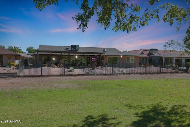 back of property at dusk featuring fence, a patio, and a yard