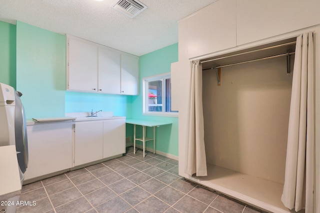 clothes washing area featuring light tile patterned floors, washer / clothes dryer, visible vents, a sink, and a textured ceiling