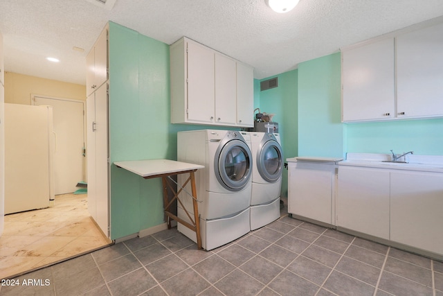 clothes washing area featuring cabinet space, visible vents, a sink, a textured ceiling, and washer and dryer