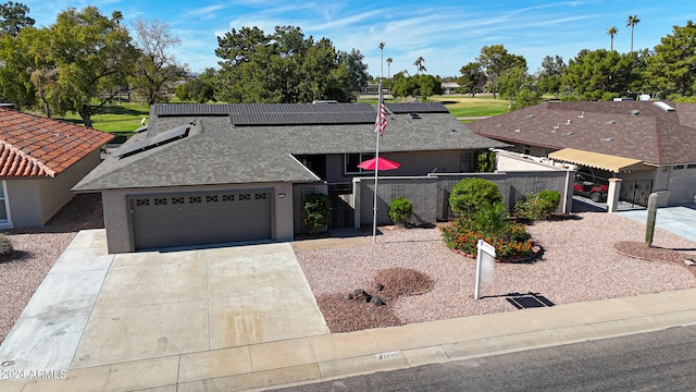 view of front of home with a garage, concrete driveway, fence, and roof mounted solar panels