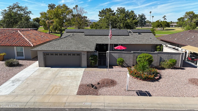 view of front of home featuring driveway, solar panels, an attached garage, fence private yard, and stucco siding