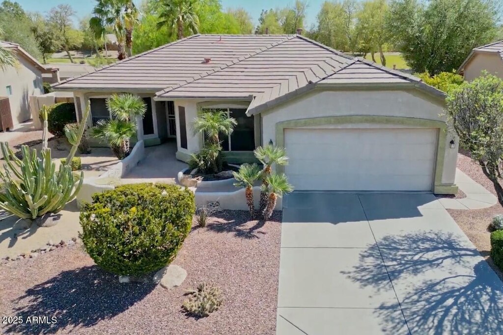 view of front of property featuring driveway, an attached garage, a tiled roof, and stucco siding