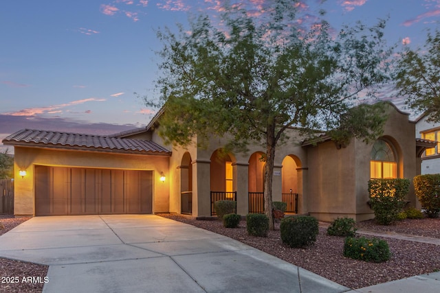 mediterranean / spanish-style house featuring fence, an attached garage, stucco siding, concrete driveway, and a tile roof