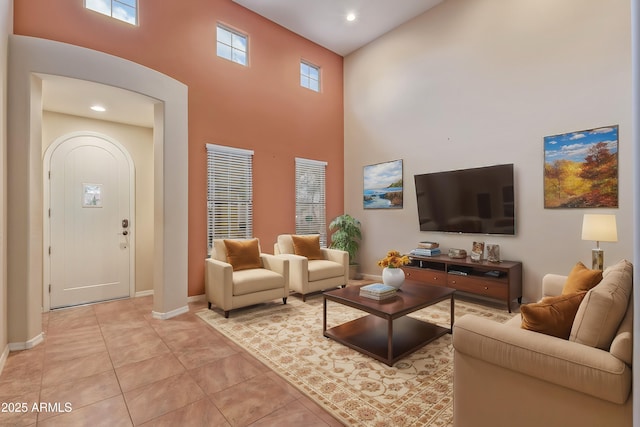 living area featuring light tile patterned floors, baseboards, a high ceiling, and recessed lighting