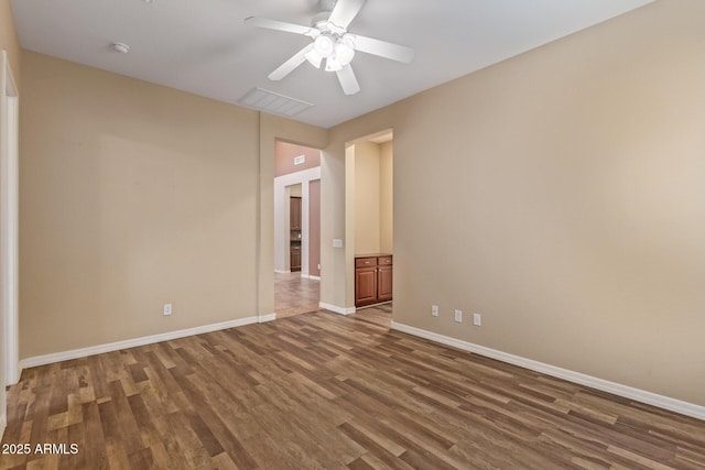 spare room with a ceiling fan, wood finished floors, visible vents, and baseboards