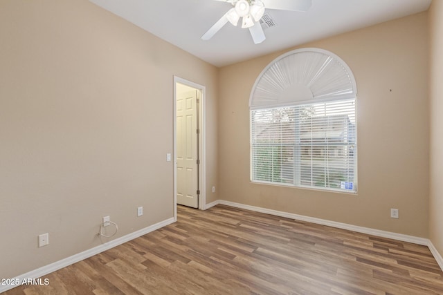 unfurnished room featuring ceiling fan, visible vents, baseboards, and wood finished floors