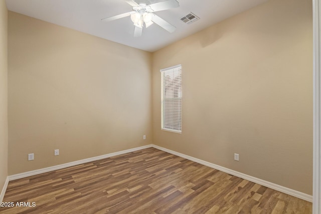 empty room featuring visible vents, baseboards, and wood finished floors