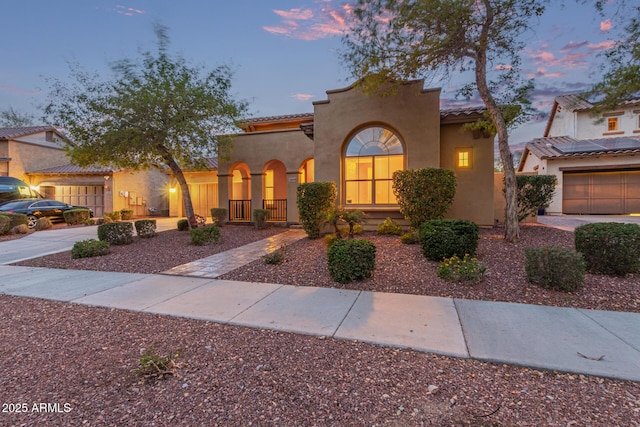 mediterranean / spanish-style house featuring a tile roof, a garage, driveway, and stucco siding