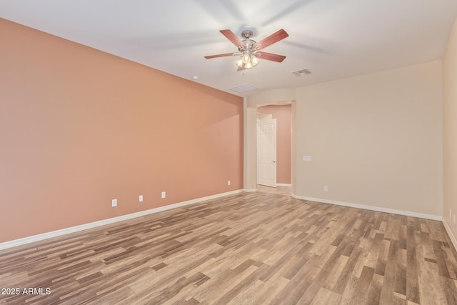 spare room featuring visible vents, baseboards, ceiling fan, and light wood finished floors