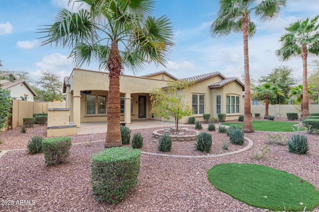 rear view of house featuring a patio, fence, and stucco siding