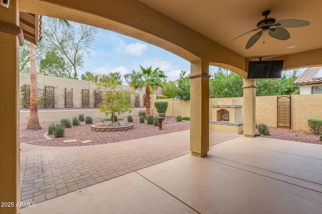 view of patio with a fenced backyard, a ceiling fan, and an outdoor fireplace