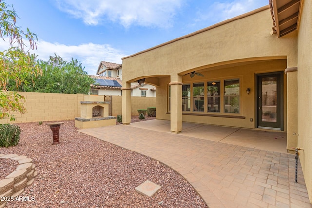 view of patio with an outdoor fireplace, a ceiling fan, and fence