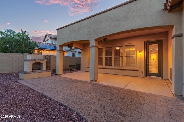 back of house with a patio, a ceiling fan, fence, stucco siding, and an outdoor fireplace