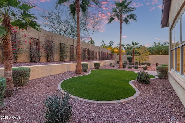 yard at dusk featuring a fenced backyard