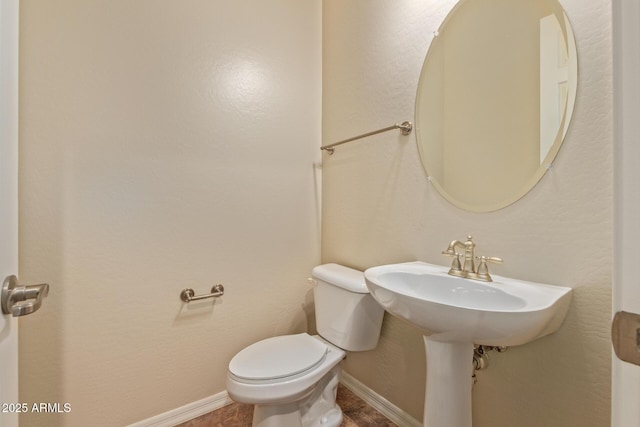 bathroom with baseboards and toilet