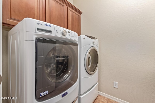 washroom with cabinet space, baseboards, a textured wall, and separate washer and dryer