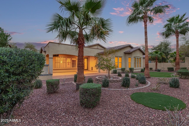 back of property at dusk featuring stucco siding