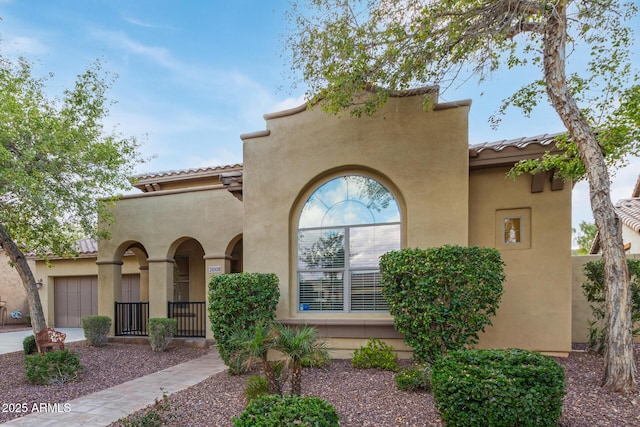 mediterranean / spanish-style house featuring stucco siding, driveway, a tile roof, and an attached garage