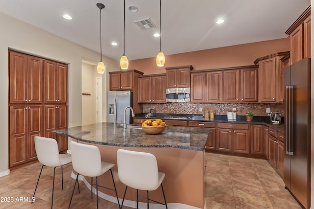 kitchen featuring visible vents, decorative backsplash, brown cabinetry, stainless steel appliances, and a sink