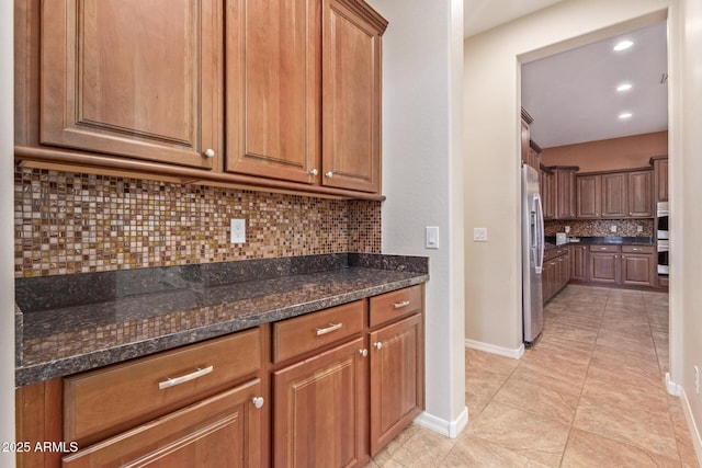 kitchen with brown cabinets, baseboards, tasteful backsplash, and stainless steel appliances