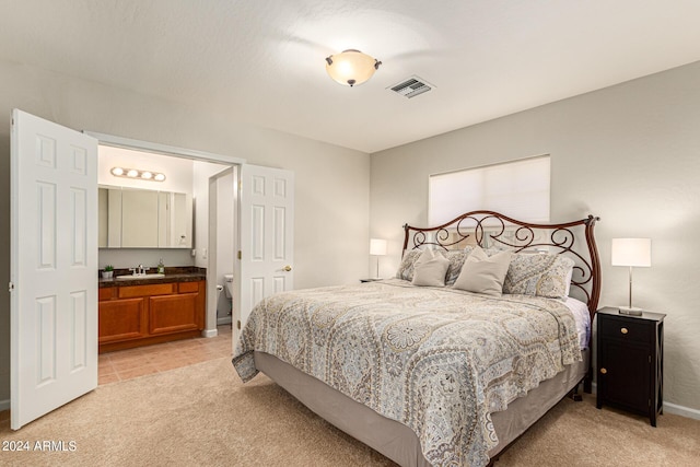 carpeted bedroom featuring ensuite bathroom and sink