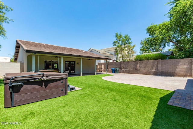 view of yard featuring a hot tub, a patio, and ceiling fan