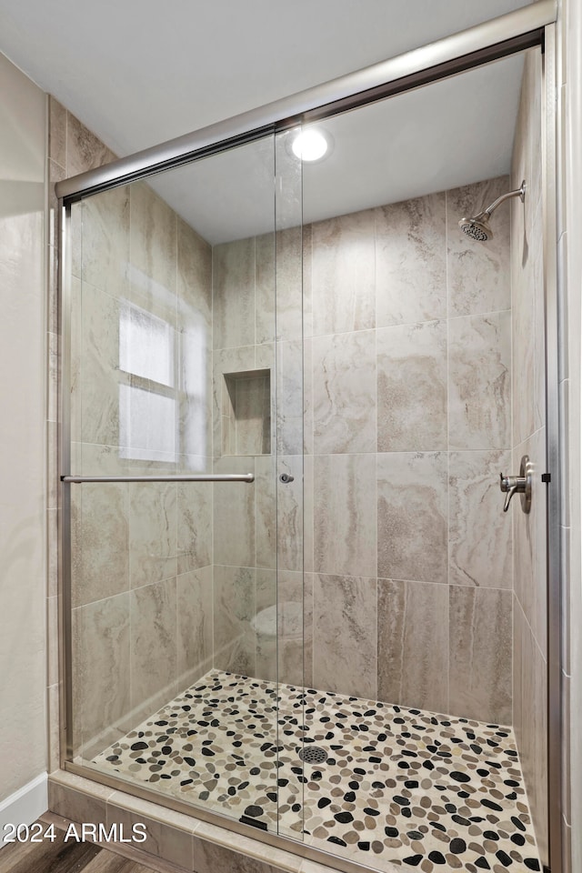 bathroom featuring wood-type flooring and an enclosed shower