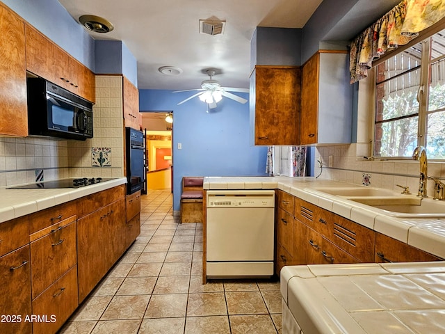 kitchen featuring a sink, a ceiling fan, light tile patterned floors, visible vents, and black appliances