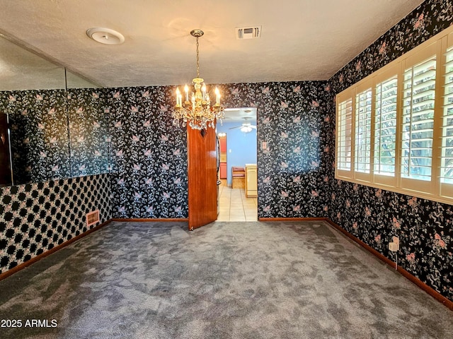 unfurnished dining area with wallpapered walls, a textured ceiling, carpet, and visible vents