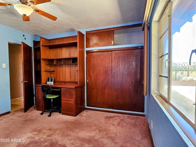 unfurnished office featuring baseboards, carpet flooring, a textured ceiling, and ceiling fan