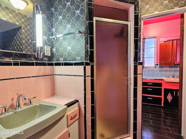 bathroom featuring a stall shower, wallpapered walls, vanity, and tile walls