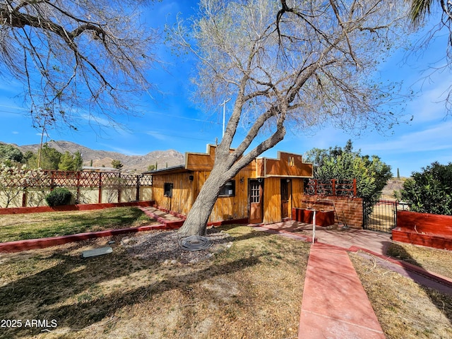 pueblo revival-style home featuring a front lawn, a gate, fence, and a mountain view