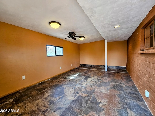 empty room featuring a ceiling fan, stone finish floor, and baseboards