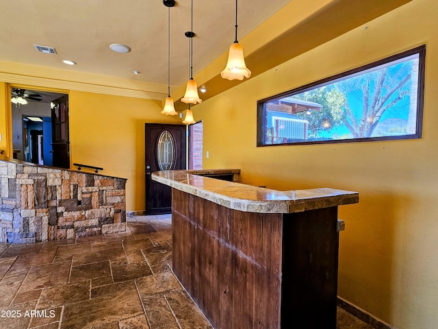 bar with visible vents, crown molding, stone tile flooring, a dry bar, and decorative light fixtures