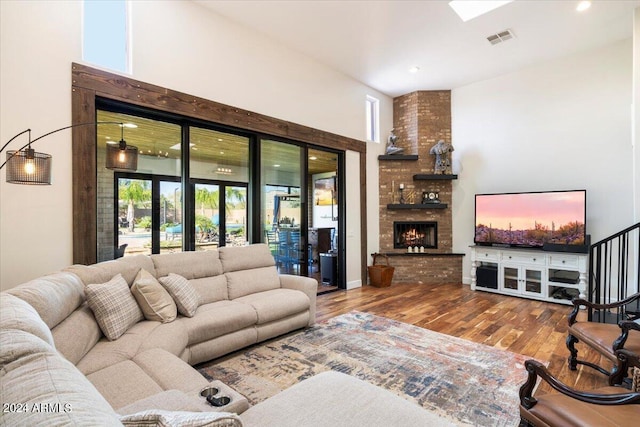 living room featuring a towering ceiling, a fireplace, and hardwood / wood-style floors