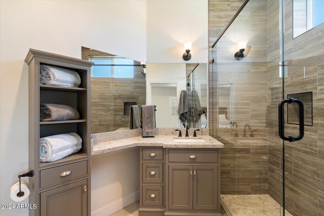 bathroom featuring a wealth of natural light, a shower with door, and vanity